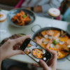 Persona tomando una foto con el móvil a una paella de marisco en un restaurante